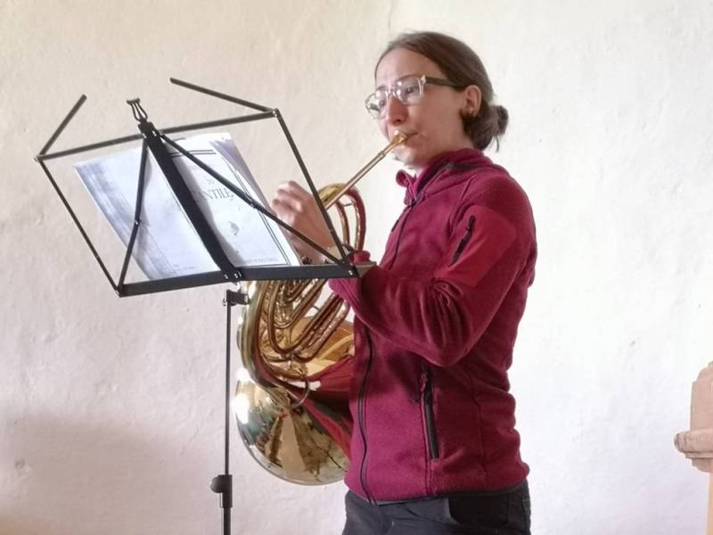 Astrid Schumacher invita, col suono del corno, al culto che si svolge nella chiesetta